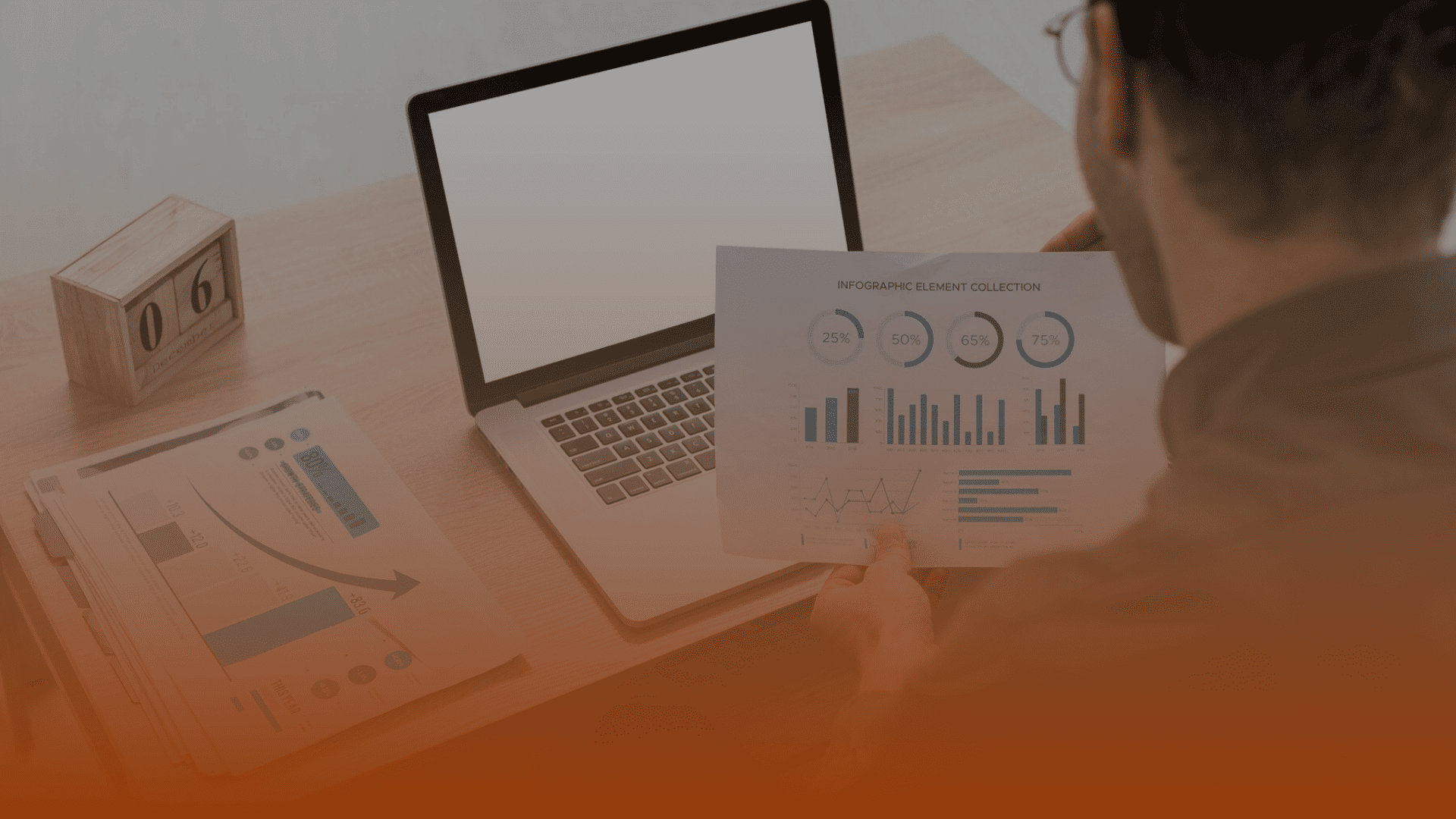 Whissel Strategies A person reviews printed charts and graphs at a desk with a laptop, documents, and a wooden calendar block displaying the number 6—analyzing data for Whissel Strategies, a leading Toronto Marketing Agency. Toronto Digital Marketing Agency