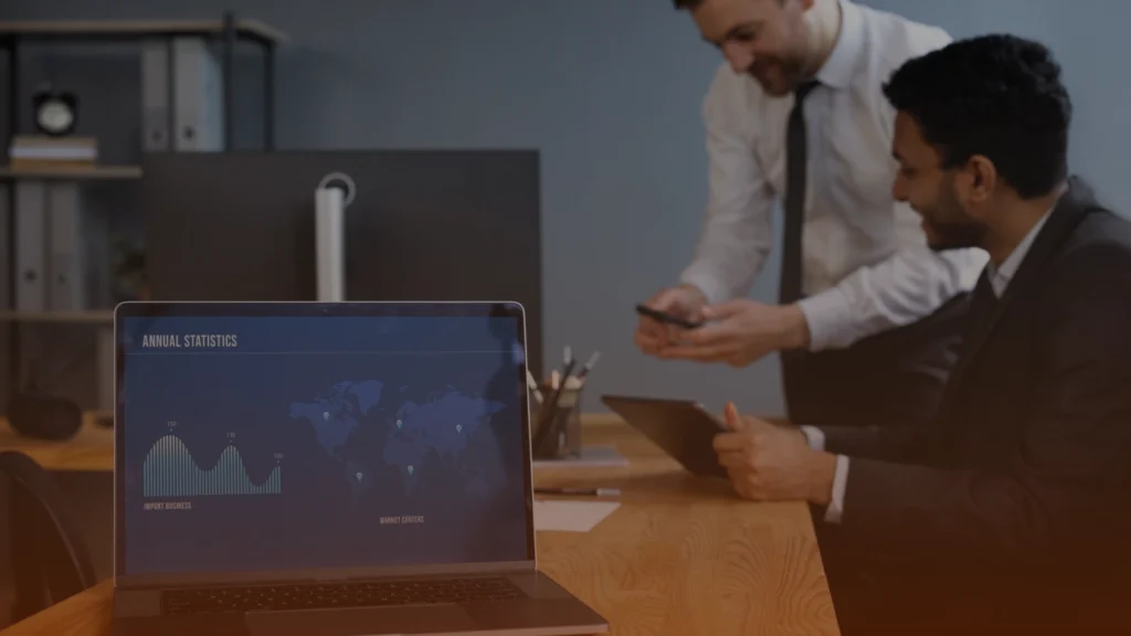 Business professionals reviewing a marketing planning agency proposal with analytics data displayed on a laptop during a strategy meeting.